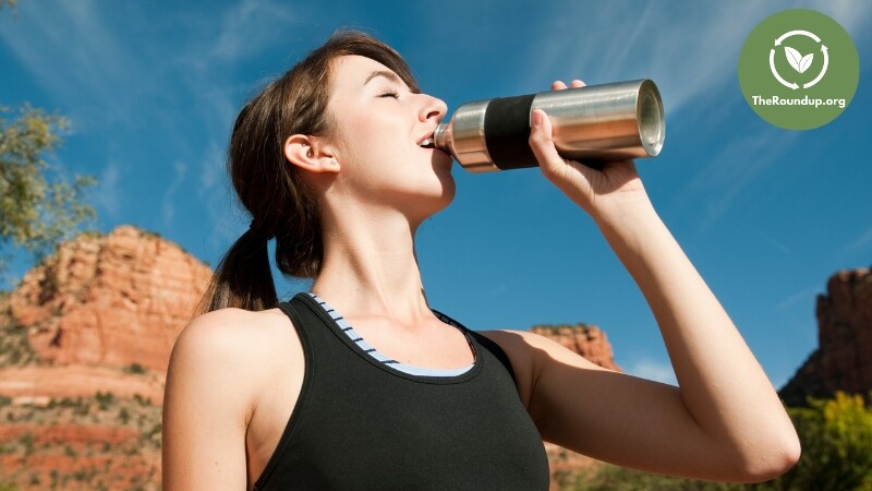woman drinking from stainless steel water bottle